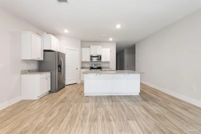 a large kitchen with stainless steel appliances a large counter top and a stove top oven