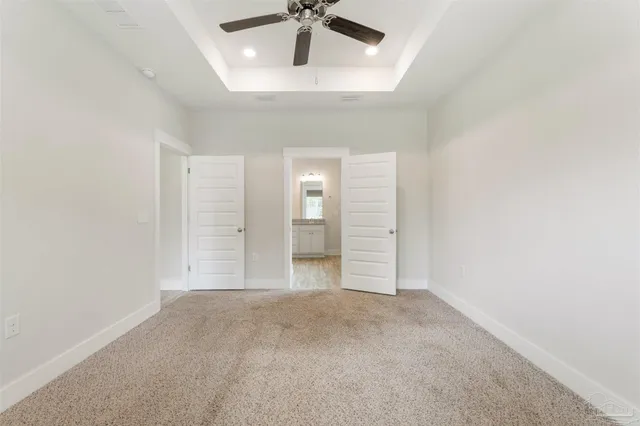 an empty room with a ceiling fan and carpet