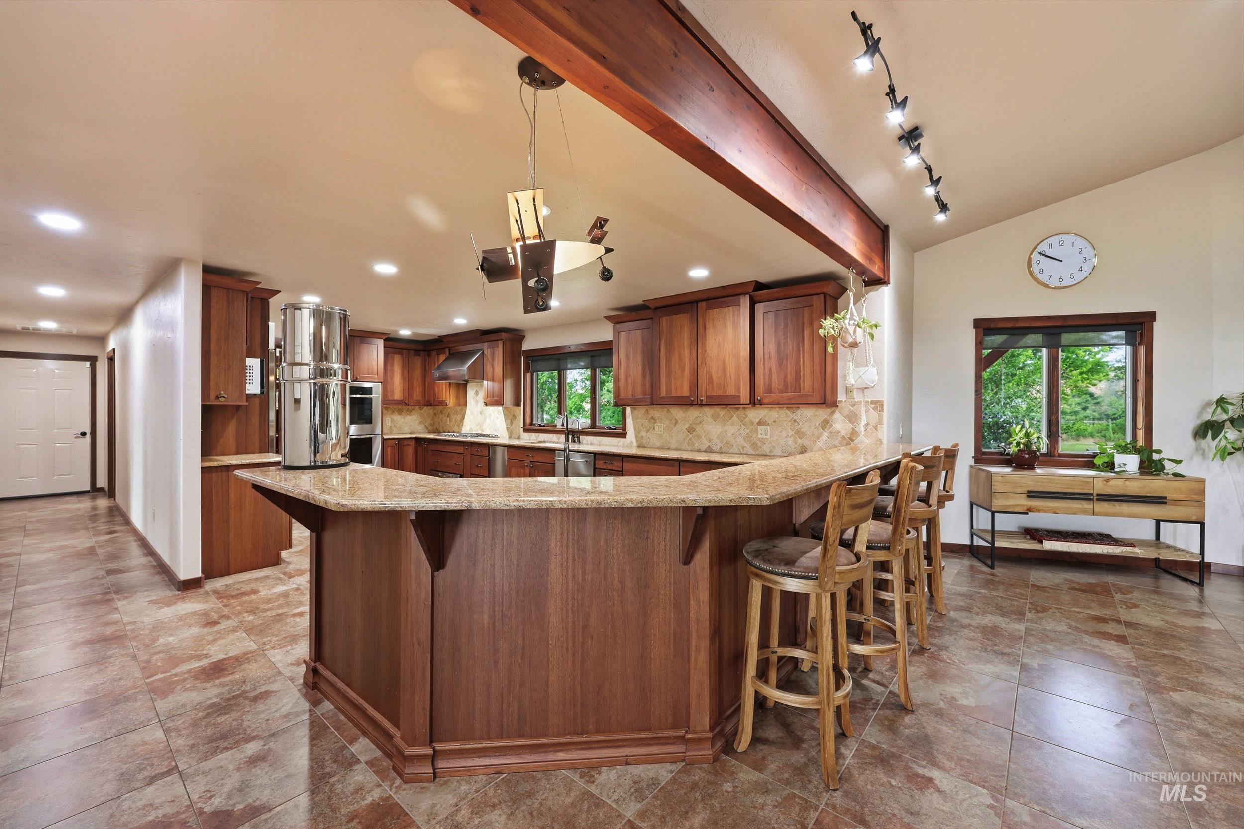 339 Airport Road Weiser, ID 83672 - Photo 11 of 49 Kitchen featuring a large central island with bar seating, wood cabinetry, stone countertops, and integrated stainless steel appliances