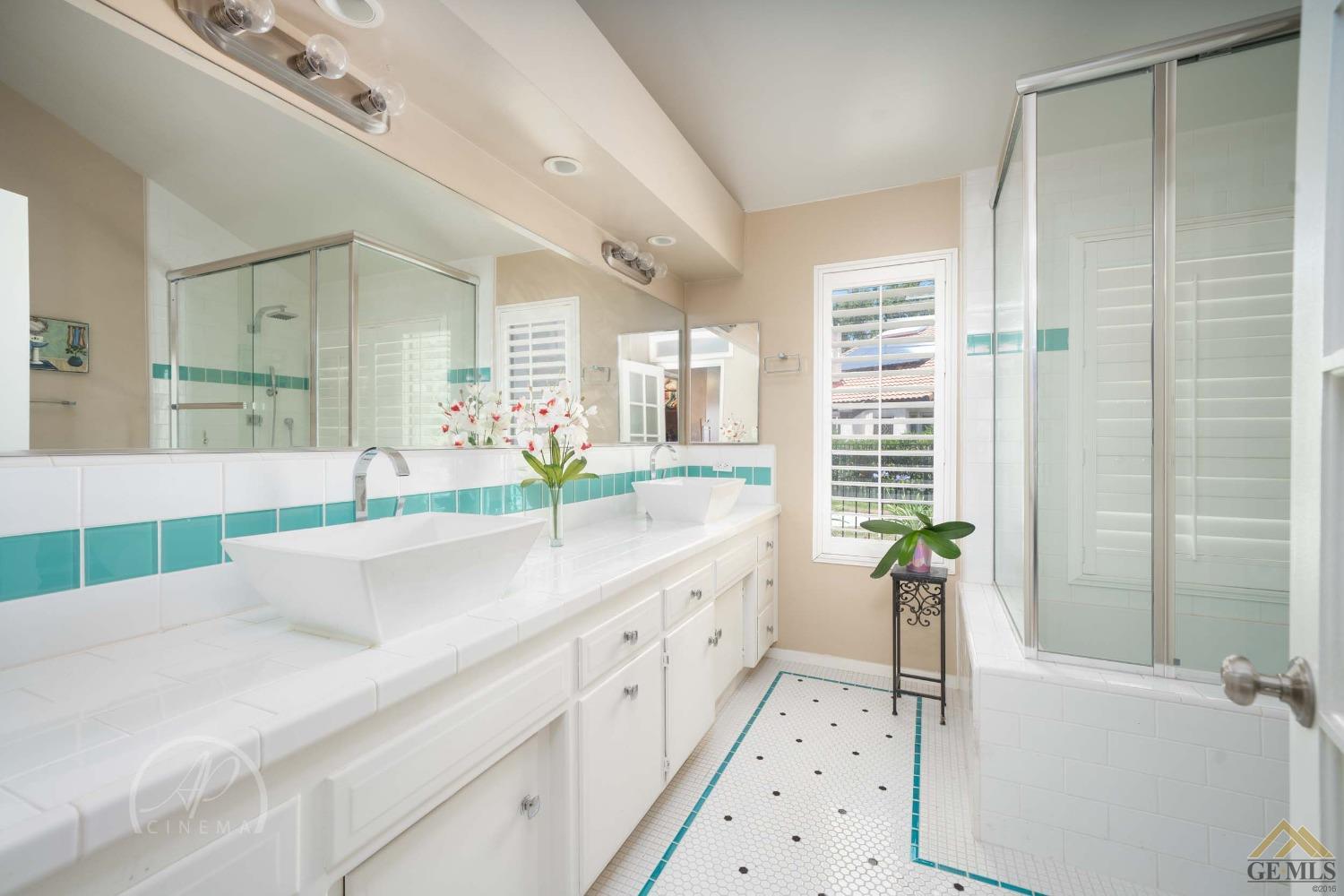 Undisclosed Address Bakersfield, CA 93309 - Photo 16 of 26 a large white bathroom with a double vanity sink a large mirror and a bathtub