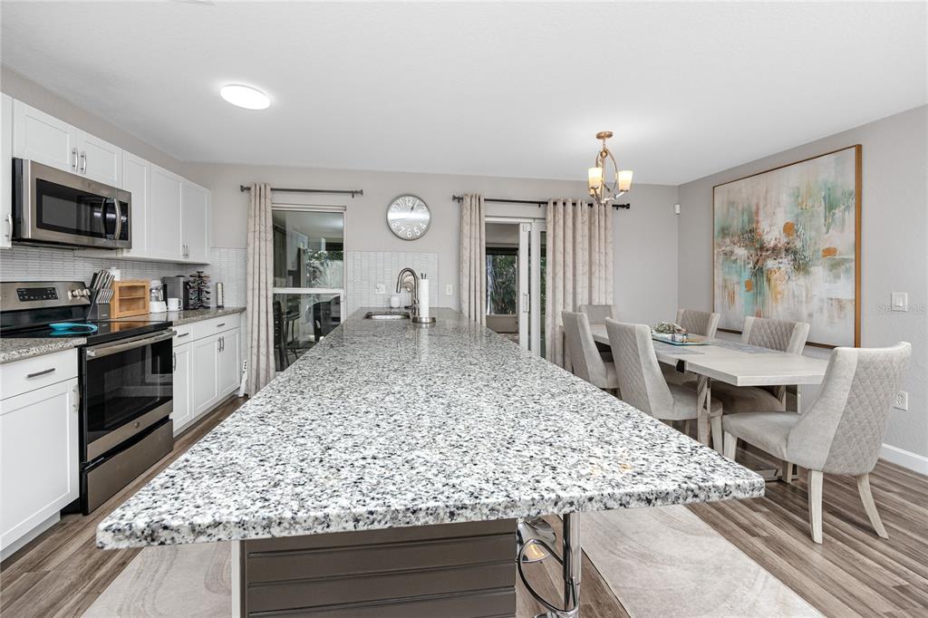 1869 Seton Drive Clearwater, FL 33763 - Photo 11 of 40 a kitchen with stainless steel appliances kitchen island granite countertop a table chairs sink and cabinets