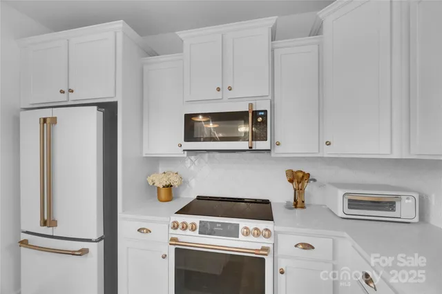 a kitchen with granite countertop white cabinets and white appliances