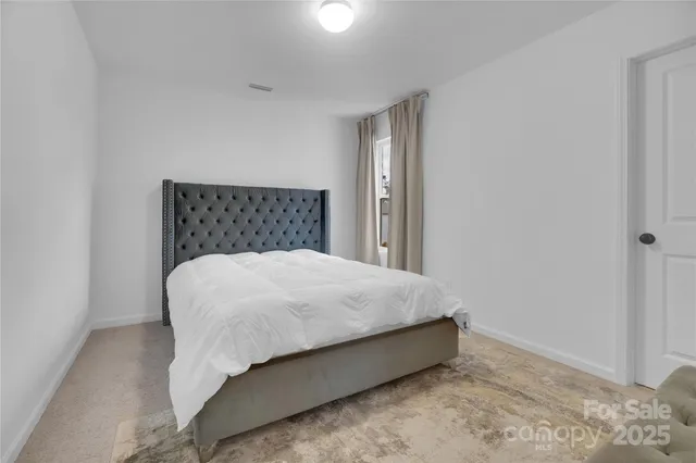 a bed sitting in a bedroom next to a window and a wooden floor