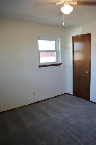 a view of a refrigerator in kitchen and an empty room in wooden floor