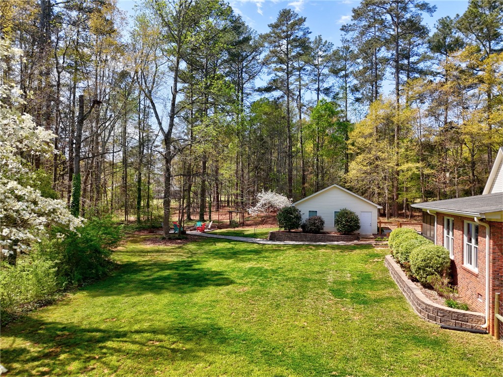 1010 Ridgeview Drive Pendleton, SC 29670 - Photo 42 of 47 A verdant yard with an outbuilding, bordered by retaining walls and mature trees.