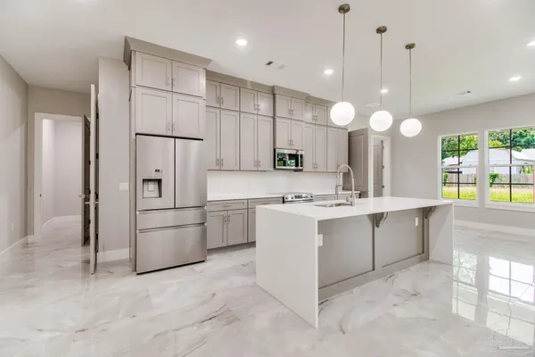 a large white kitchen with window and white cabinets