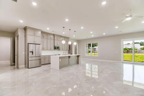 a large kitchen with kitchen island a large counter top space a sink stainless steel appliances and cabinets