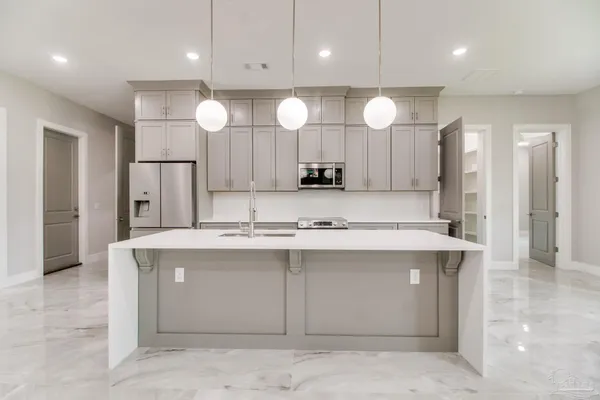 a view of a kitchen with kitchen island a sink appliances and a chandelier