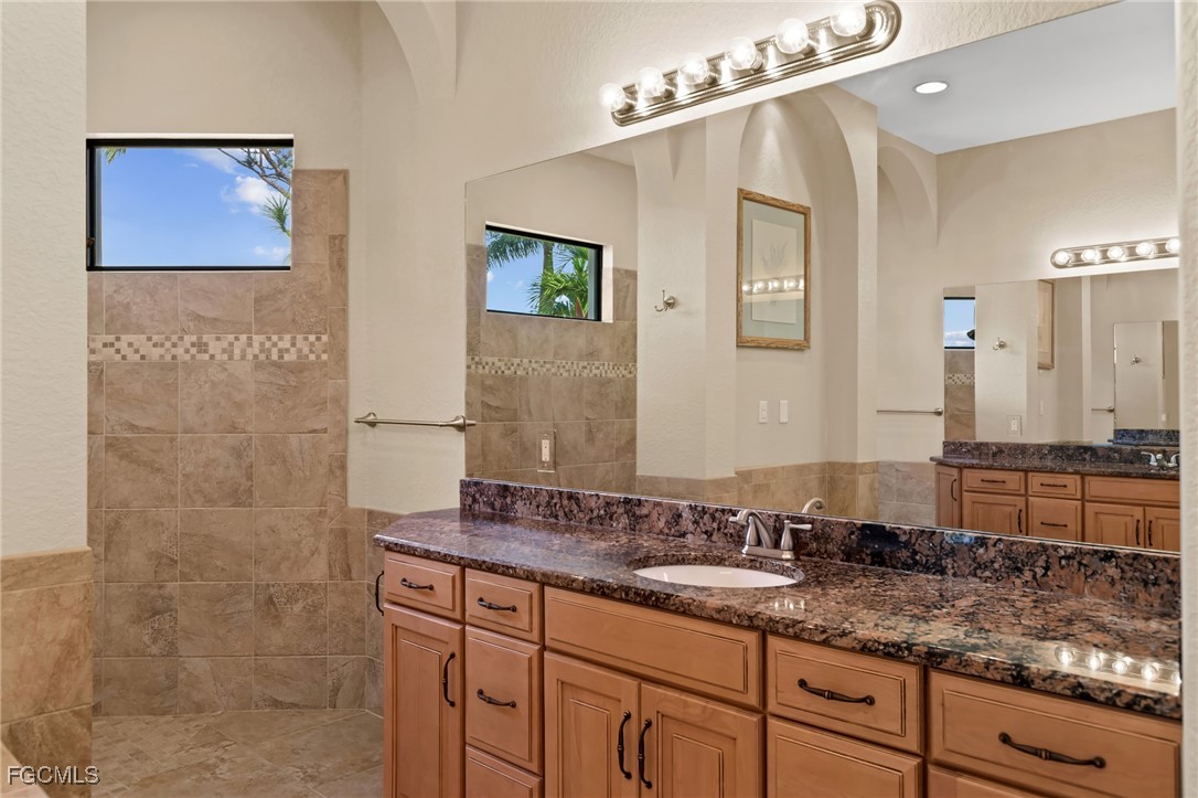 6057 Calusa Rdg Trail Bokeelia, FL 33922 - Photo 18 of 45 a bathroom with a granite countertop sink a mirror and shower