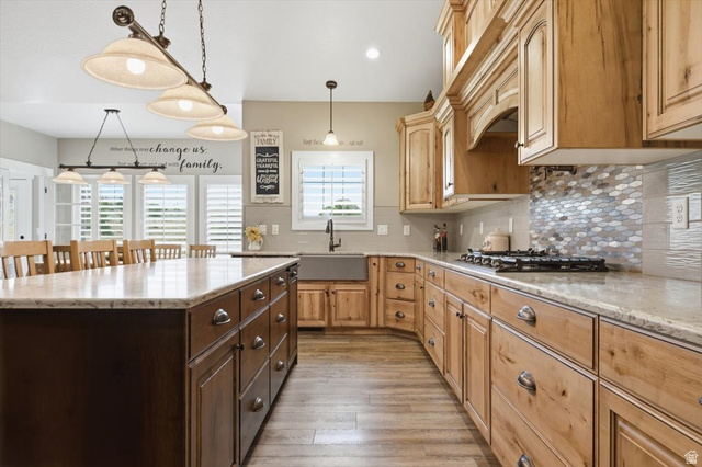 3123 East Riverdale Road Preston, ID 83263 - Photo 12 of 52 Spacious kitchen featuring light wood cabinetry, stone countertops, a large center island with dark wood base, wood-finish flooring, and a patterned tile backsplash
