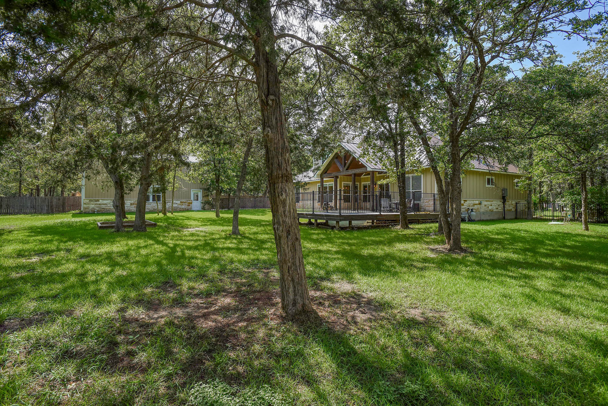 115 Pine Point Cove Elgin, TX 78621 - Photo 39 of 39 Mature trees shade a spacious green lawn, framing a welcoming back porch ideal for outdoor enjoyment.