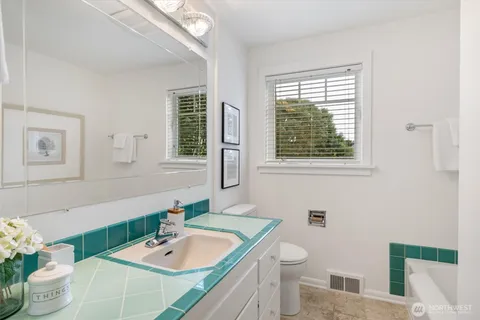 a bath room with a toilet a sink and a mirror