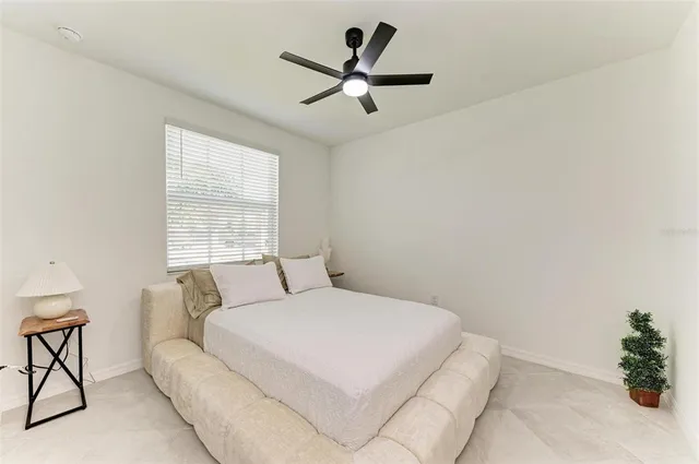 a bedroom with a large bed and ceiling fan
