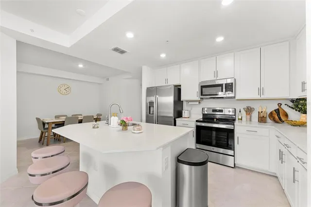a kitchen with stainless steel appliances kitchen island a table and chairs