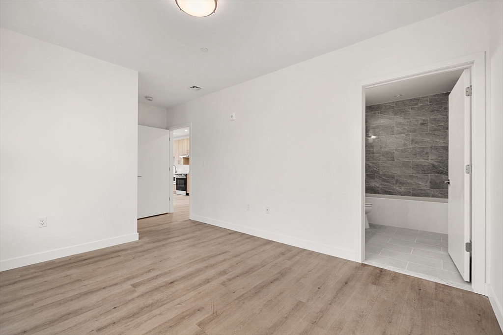 1151 Walnut Street, Unit 301 Newton, MA 02461 - Photo 6 of 14 an empty room with wooden floor and windows