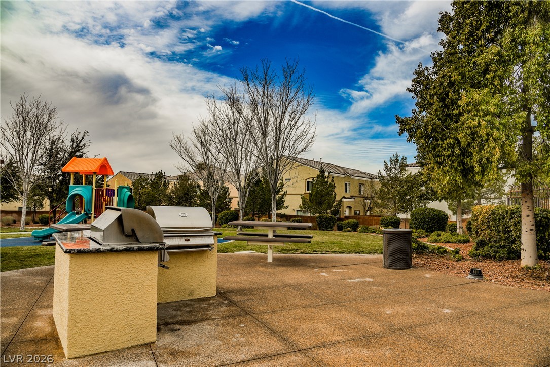 6320 Snap Ridge Street, Unit 201 North Las Vegas, NV 89081 - Photo 46 of 56 Enjoy outdoor gatherings with a built-in barbecue and picnic area set against a vibrant green space and residential backdrop.