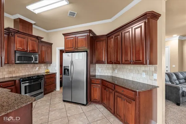 a kitchen with stainless steel appliances granite countertop a refrigerator a stove a sink and a microwave