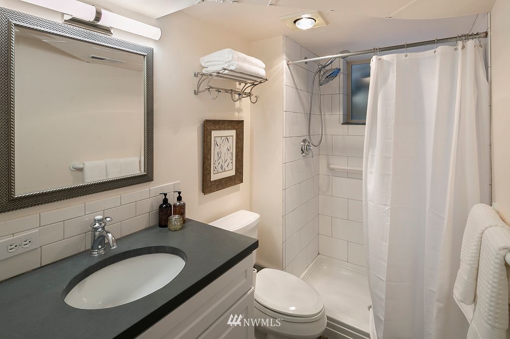 2801 28th Avenue West Seattle, WA 98199 - Photo 31 of 39 a bathroom with a granite countertop sink toilet a mirror a vanity and shower