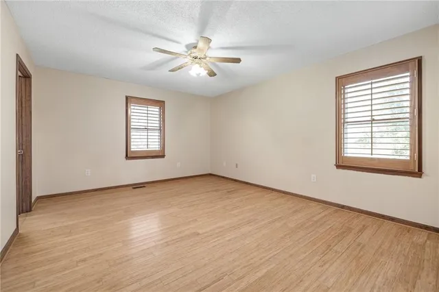 a view of an empty room with a window and wooden floor