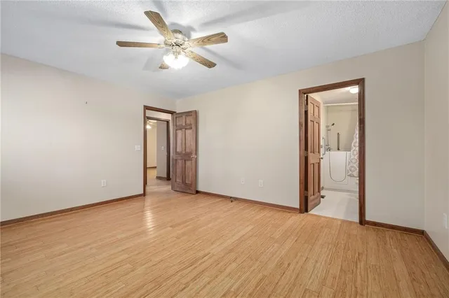 an empty room with wooden floor and ceiling fan