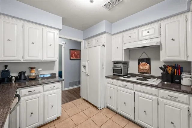 a kitchen with granite countertop white cabinets and refrigerator