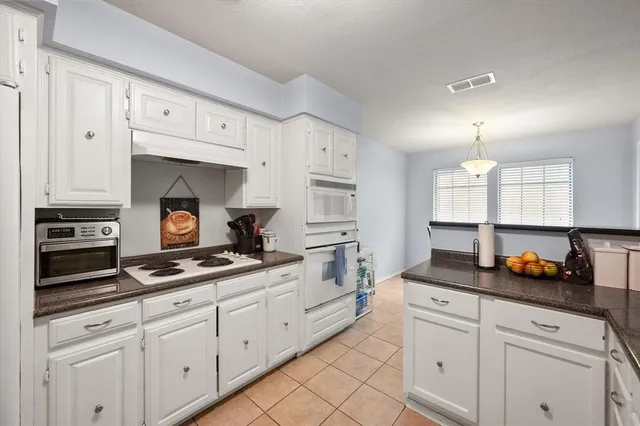 a kitchen with white cabinets and appliances