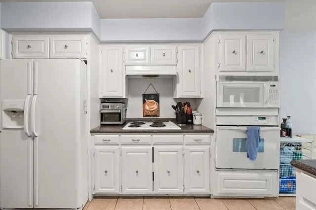 a kitchen with granite countertop white cabinets and refrigerator