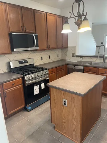 a kitchen with stainless steel appliances a stove a microwave and a sink