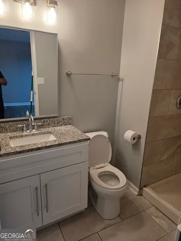a bathroom with a granite countertop toilet and a sink