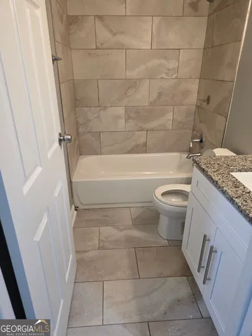 a bathroom with a granite countertop bathtub and toilet