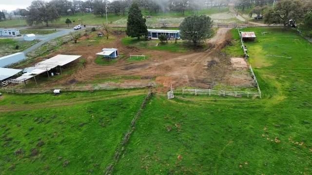 an aerial view of residential houses with outdoor space and trees