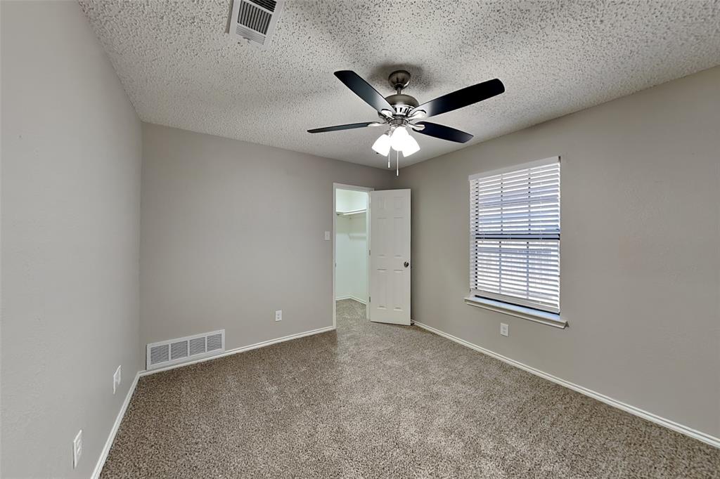 3920 Winston Drive Denton, TX 76210 - Photo 14 of 20 Unfurnished bedroom featuring a walk in closet, carpet flooring, ceiling fan, and a textured ceiling