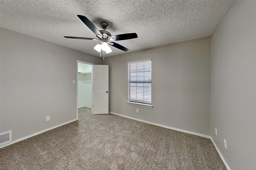 3920 Winston Drive Denton, TX 76210 - Photo 15 of 20 Unfurnished bedroom with a walk in closet, carpet, a ceiling fan, and a textured ceiling
