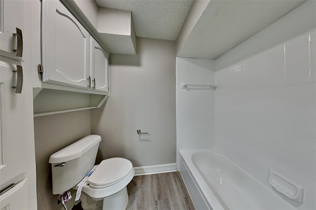 3920 Winston Drive Denton, TX 76210 - Photo 18 of 20 Bathroom featuring light wood-type flooring, a textured ceiling, and washtub / shower combination