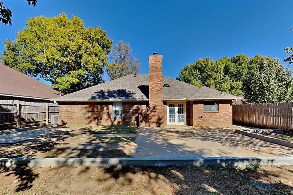 3920 Winston Drive Denton, TX 76210 - Photo 19 of 20 Rear view of property featuring a fenced backyard, french doors, brick siding, a chimney, and a shingled roof