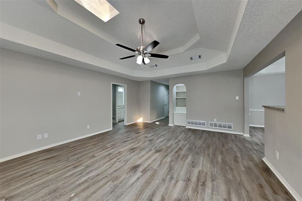 3920 Winston Drive Denton, TX 76210 - Photo 3 of 20 Spare room featuring wood finished floors, a tray ceiling, a textured ceiling, a skylight, and a ceiling fan