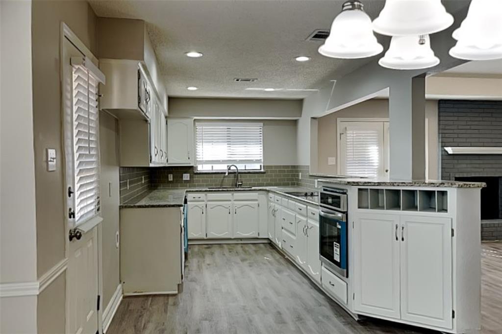 3920 Winston Drive Denton, TX 76210 - Photo 5 of 20 Kitchen with dark stone countertops, white cabinets, stainless steel oven, light wood-type flooring, and hanging light fixtures