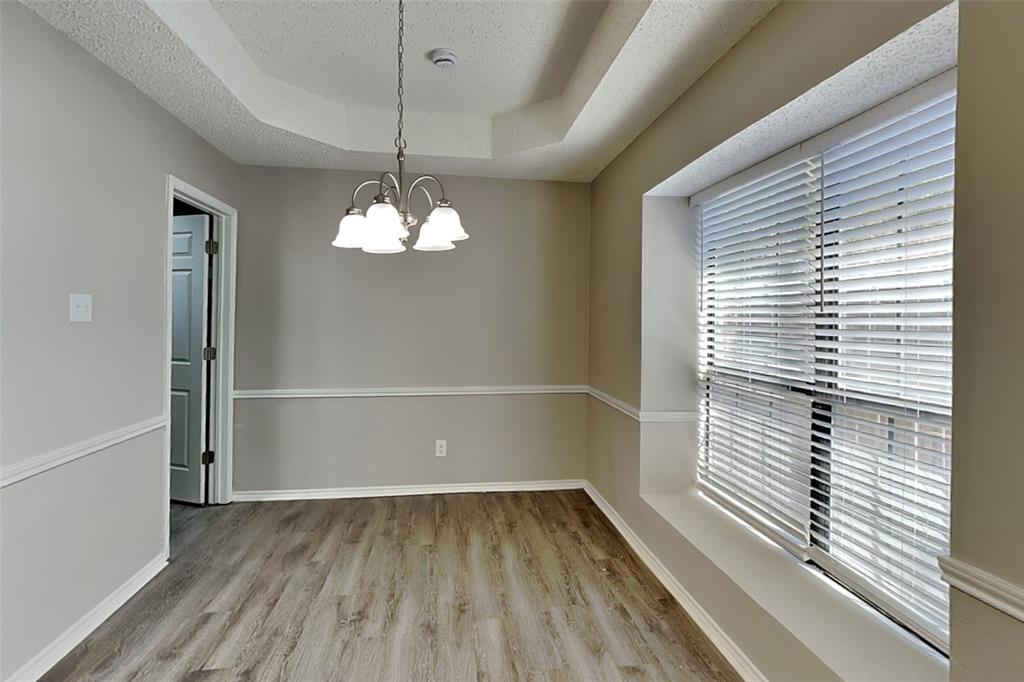 3920 Winston Drive Denton, TX 76210 - Photo 7 of 20 Spare room featuring a raised ceiling, light wood-style floors, a chandelier, and a textured ceiling