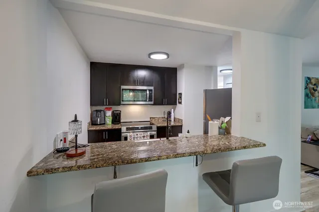 a kitchen with granite countertop stainless steel appliances a sink stove and refrigerator