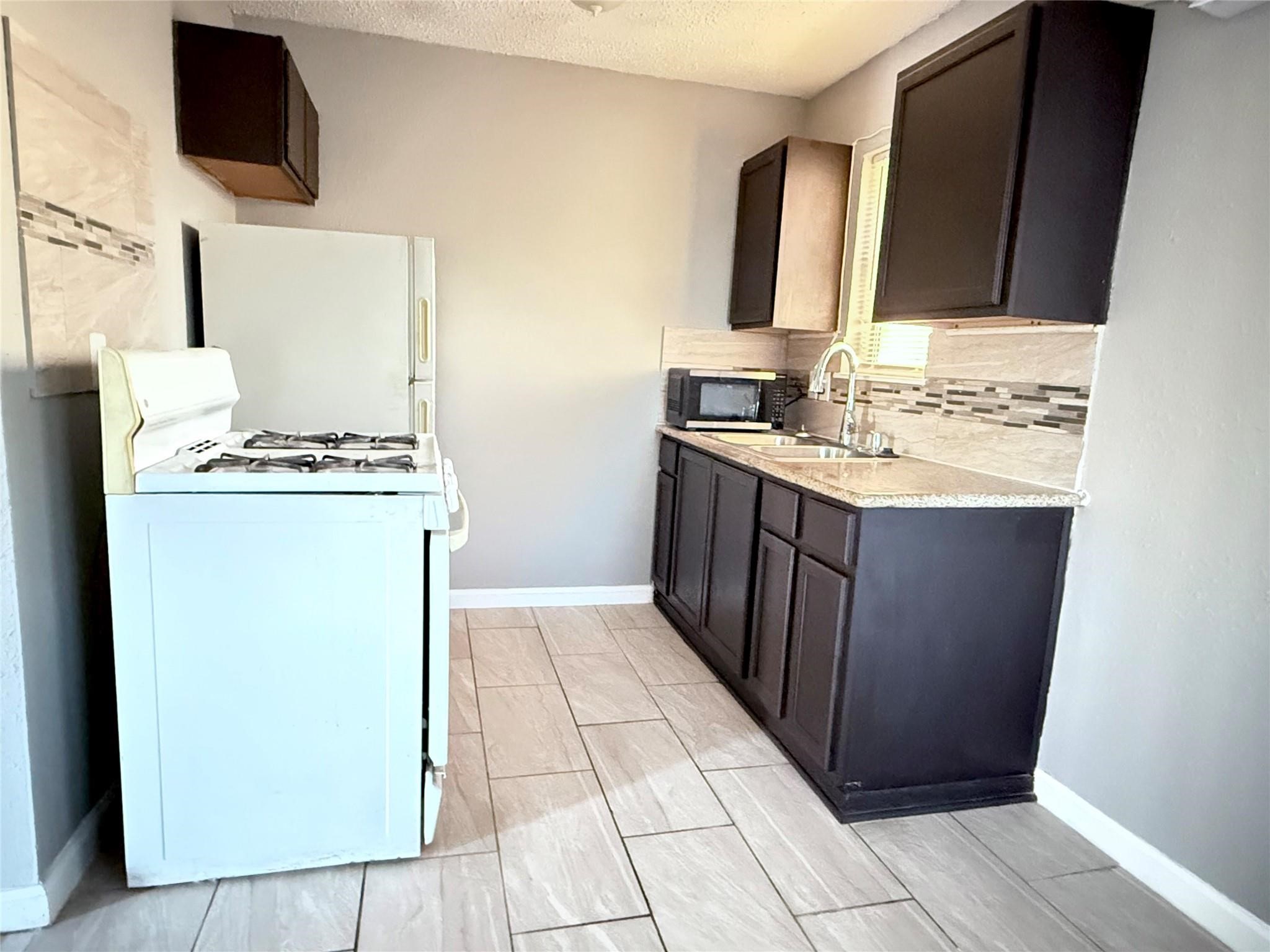 5418 Weaver Road, Unit D Houston, TX 77016 - Photo 4 of 10 a kitchen with a sink stove and microwave