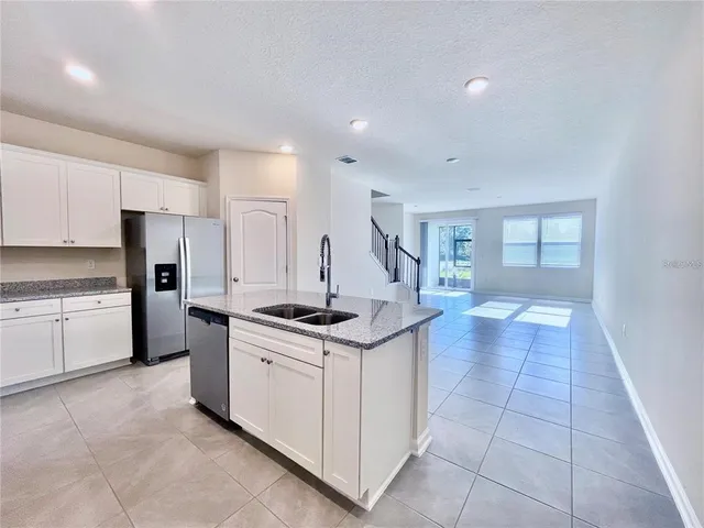 a kitchen that has a lot of white cabinets and stainless steel appliances