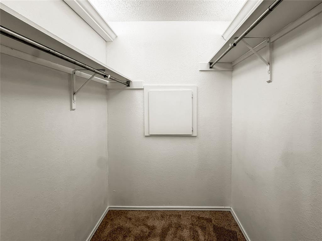 5840 Spring Valley Road, Unit 602 Dallas, TX 75254 - Photo 12 of 19 Interior closet featuring two metal hanging rods, overhead shelving, crown molding, and brown carpet flooring