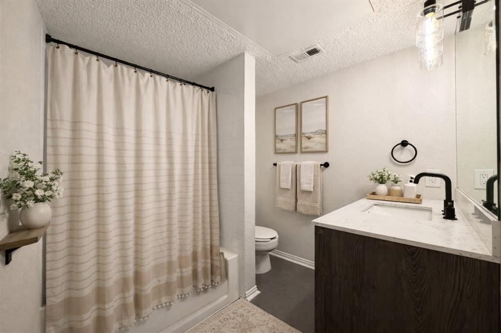 5840 Spring Valley Road, Unit 602 Dallas, TX 75254 - Photo 17 of 19 Contemporary bathroom featuring a wood-finish vanity with a white countertop and integrated sink