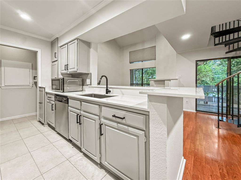 5840 Spring Valley Road, Unit 602 Dallas, TX 75254 - Photo 3 of 19 Kitchen featuring white cabinetry, white countertops, a stainless steel sink with a black faucet, and tile flooring
