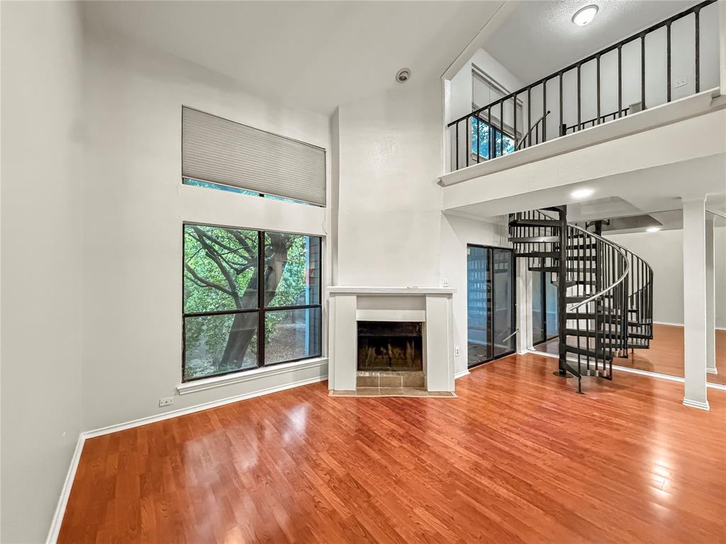 5840 Spring Valley Road, Unit 602 Dallas, TX 75254 - Photo 7 of 19 Living space featuring wood-finish flooring, a white fireplace with a tiled hearth, and large windows