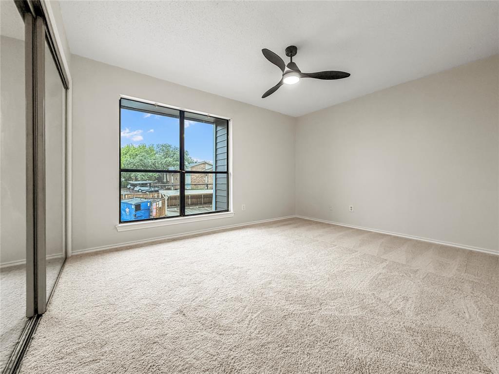 5840 Spring Valley Road, Unit 602 Dallas, TX 75254 - Photo 10 of 19 Spacious room featuring light-colored carpeting, neutral wall tones, a contemporary ceiling fan with integrated lighting, and a large window with black framing