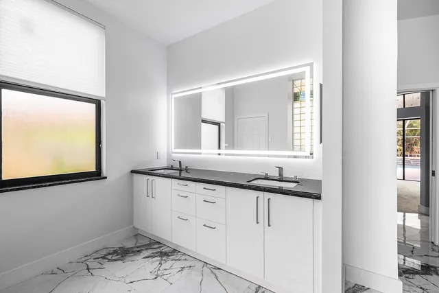 a bathroom with a granite countertop sink and a window