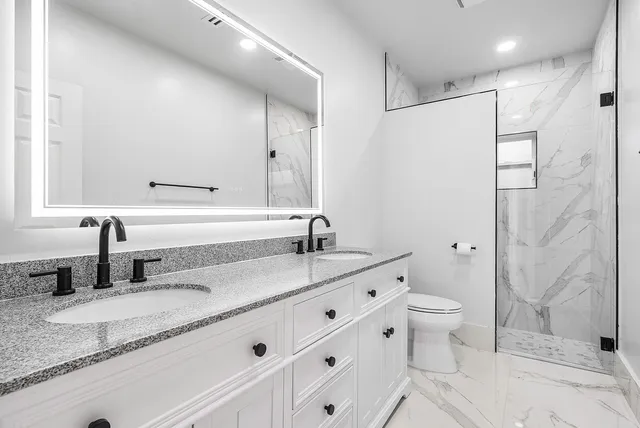 a bathroom with a sink a toilet and shower