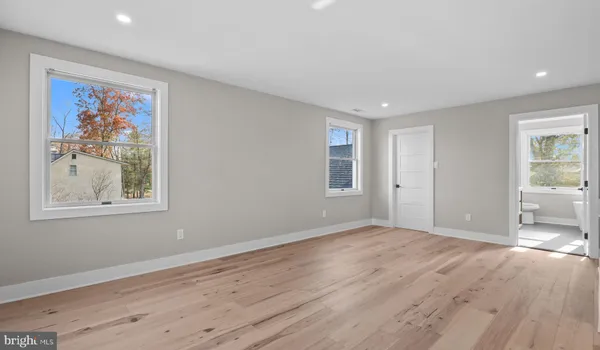 a view of an empty room with wooden floor and window