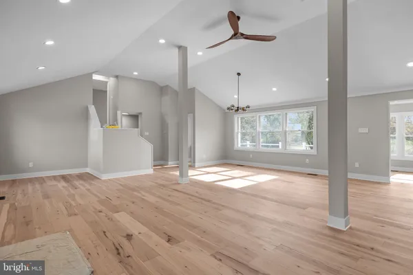 a view of an empty room with wooden floor and a kitchen